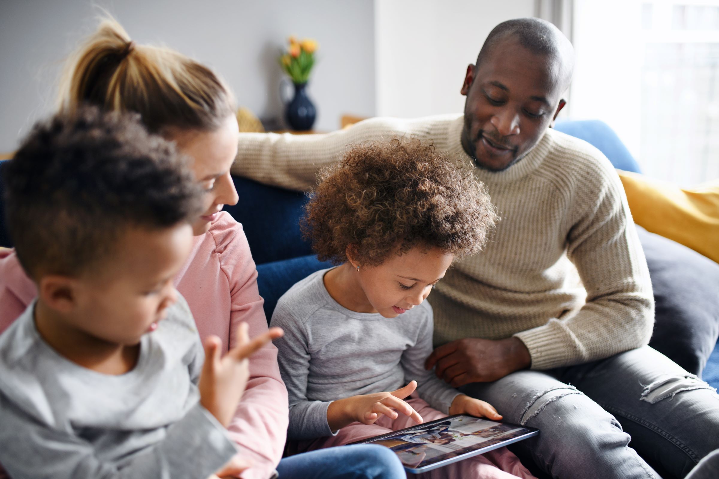 Parents and children engaging in a digital literacy activity together at home.