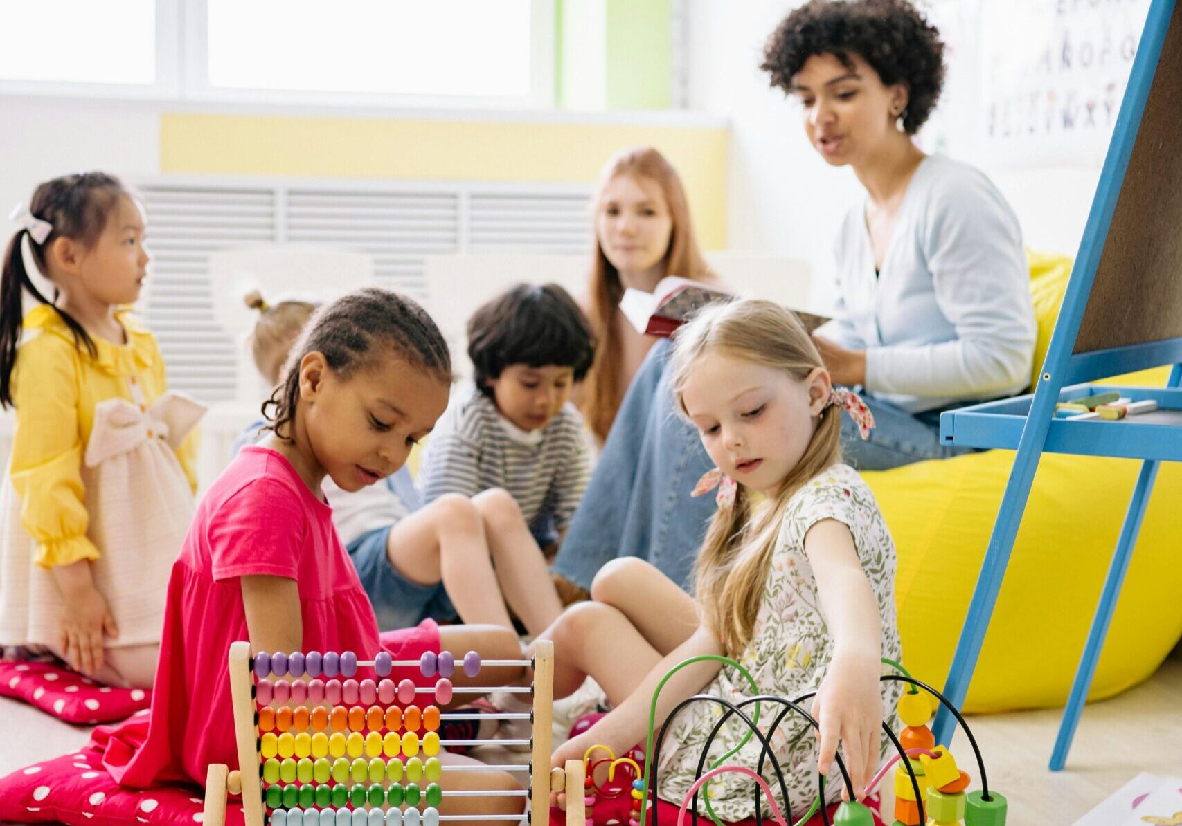 Preschool students practicing fine motor skills and pattern recognition using wooden bead mazes and an abacus.